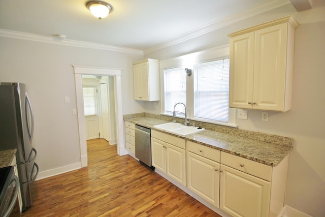 kitchen featuring ornamental molding, stainless steel appliances, light wood finished floors, and a sink