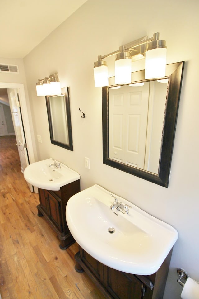 bathroom with visible vents, wood finished floors, and two sinks