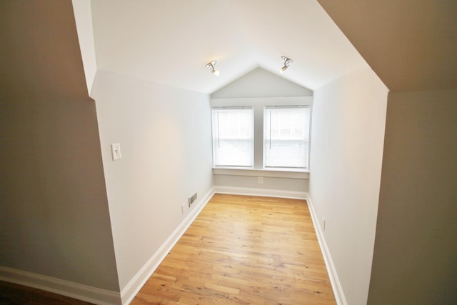 additional living space with lofted ceiling, light wood-style floors, baseboards, and visible vents