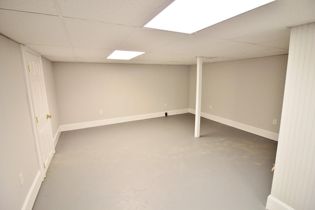 finished basement featuring baseboards and a drop ceiling