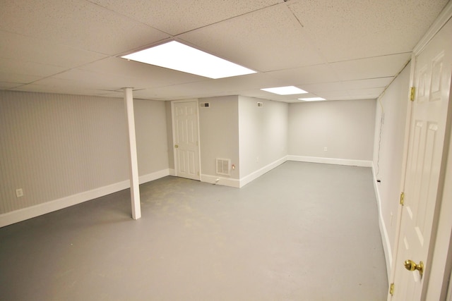 finished basement with a paneled ceiling, visible vents, and baseboards