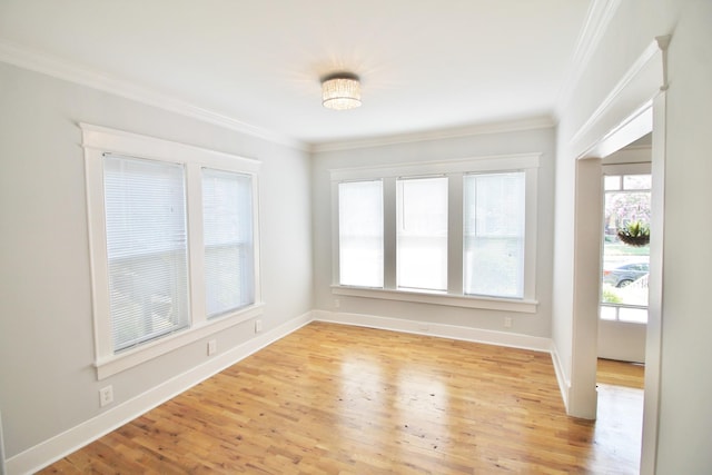 empty room with baseboards, crown molding, and light wood finished floors