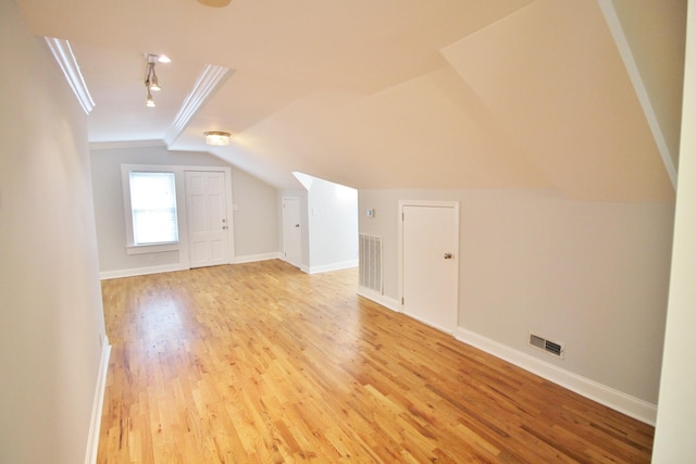 additional living space with light wood finished floors, visible vents, baseboards, and lofted ceiling