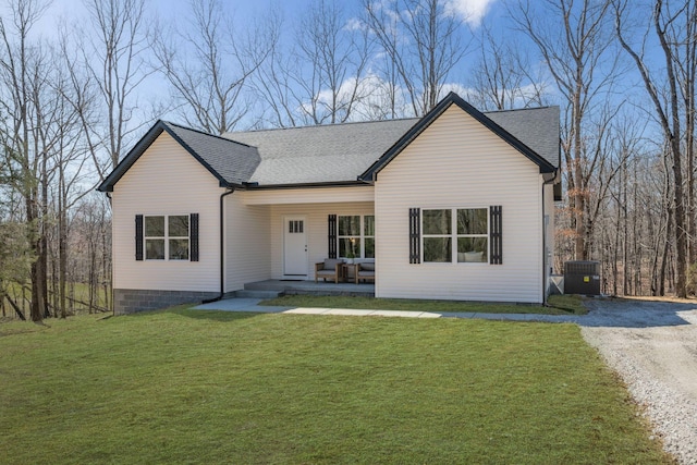 view of front of house featuring a shingled roof, gravel driveway, a front lawn, central AC, and covered porch