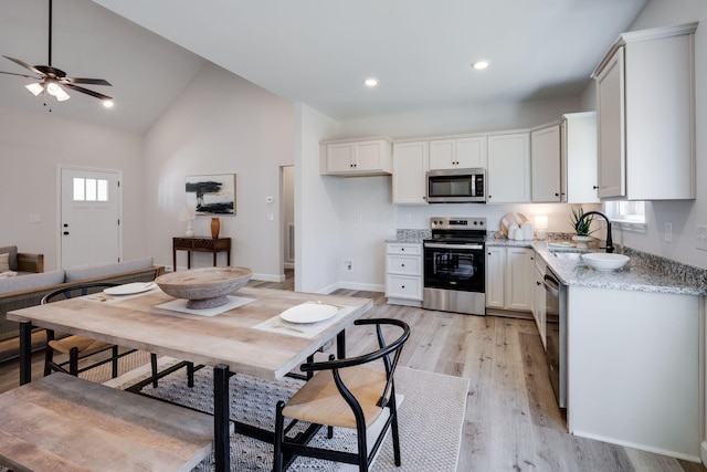 kitchen with light wood finished floors, recessed lighting, a sink, stainless steel appliances, and vaulted ceiling