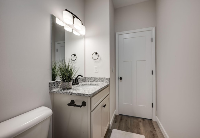 bathroom featuring vanity, toilet, wood finished floors, and baseboards