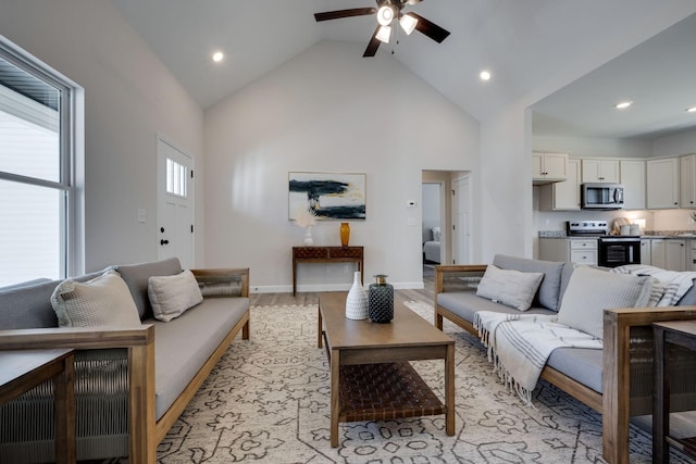 living area featuring high vaulted ceiling, recessed lighting, light wood-style floors, baseboards, and ceiling fan