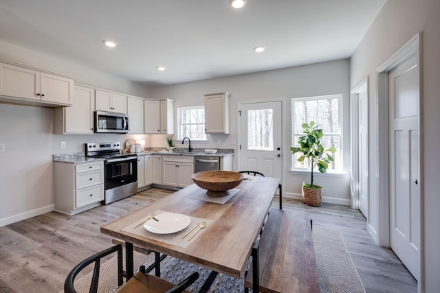 kitchen featuring baseboards, light wood-style flooring, recessed lighting, stainless steel appliances, and white cabinetry