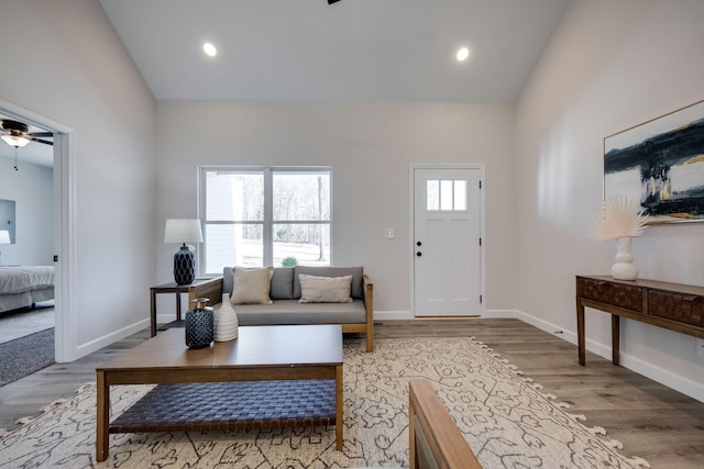 living room featuring lofted ceiling, recessed lighting, wood finished floors, and baseboards