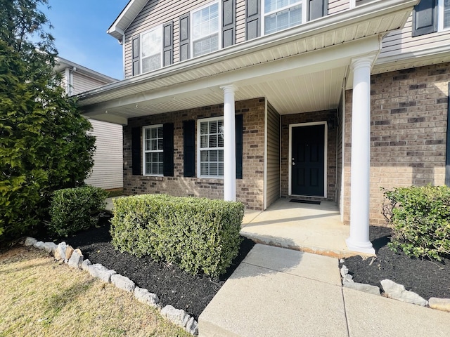 property entrance featuring brick siding and a porch