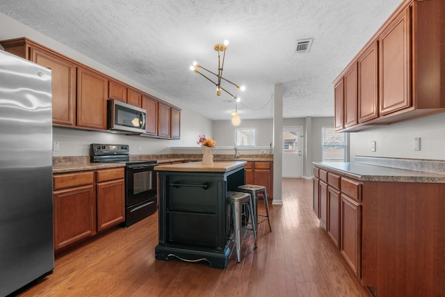 kitchen featuring brown cabinetry, wood finished floors, and stainless steel appliances