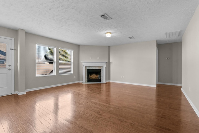 unfurnished living room with a premium fireplace, visible vents, baseboards, and wood finished floors