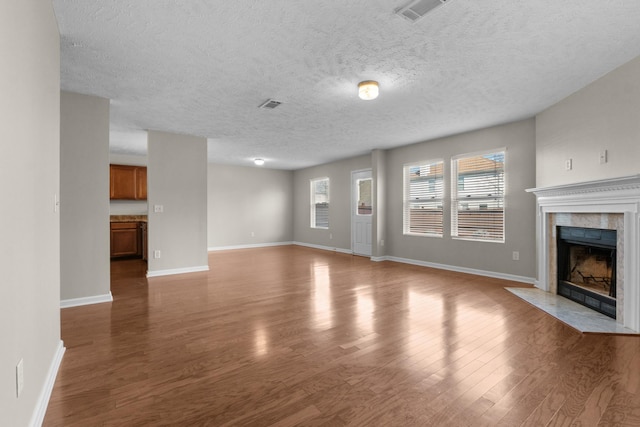 unfurnished living room with visible vents, a tile fireplace, and wood finished floors