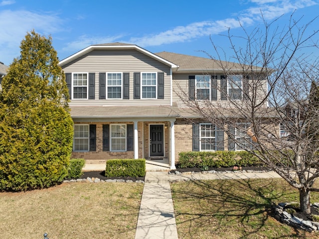 traditional home with a front lawn, covered porch, and brick siding