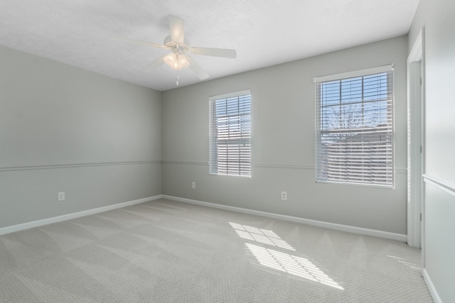 empty room featuring a textured ceiling, carpet flooring, baseboards, and ceiling fan