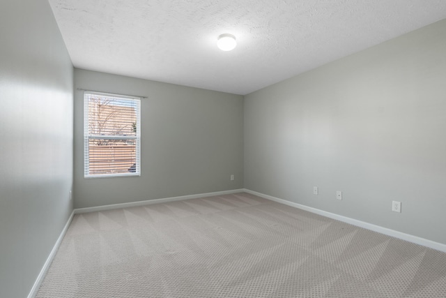 unfurnished room with baseboards, light colored carpet, and a textured ceiling