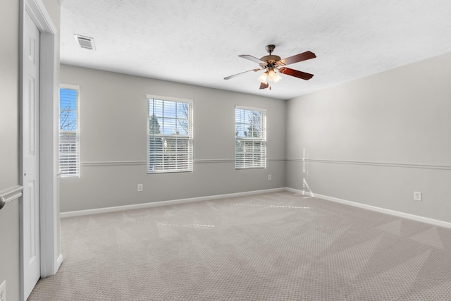 unfurnished room featuring baseboards, visible vents, a textured ceiling, and ceiling fan