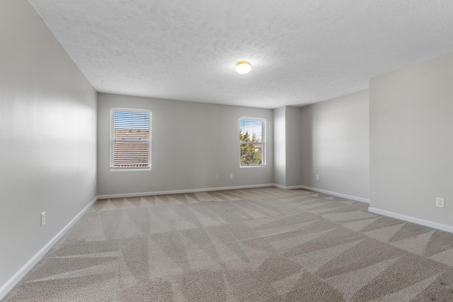 unfurnished room with light carpet, a textured ceiling, and baseboards