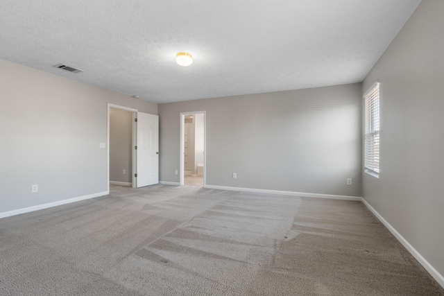 carpeted spare room with baseboards, visible vents, and a textured ceiling