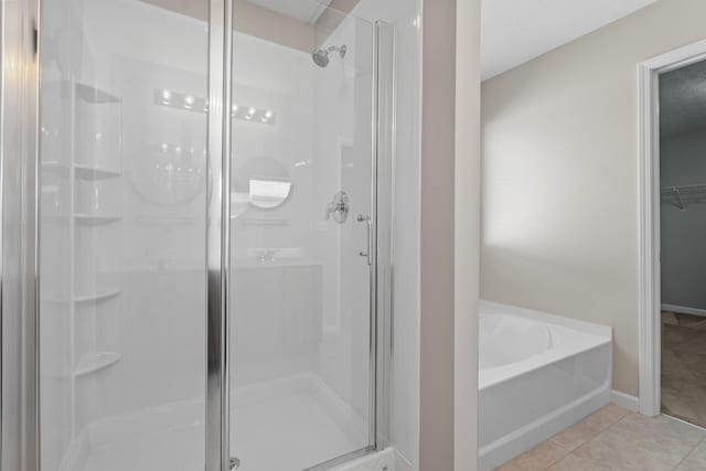 bathroom with baseboards, a bath, a stall shower, and tile patterned flooring