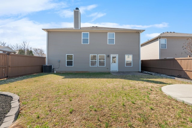 back of property featuring a yard, cooling unit, a fenced backyard, and a chimney