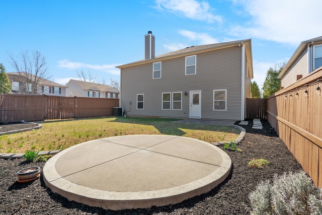 rear view of house featuring a fenced backyard, a yard, cooling unit, a chimney, and a patio area