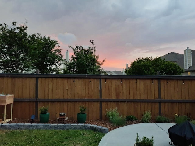 yard at dusk with a patio and fence