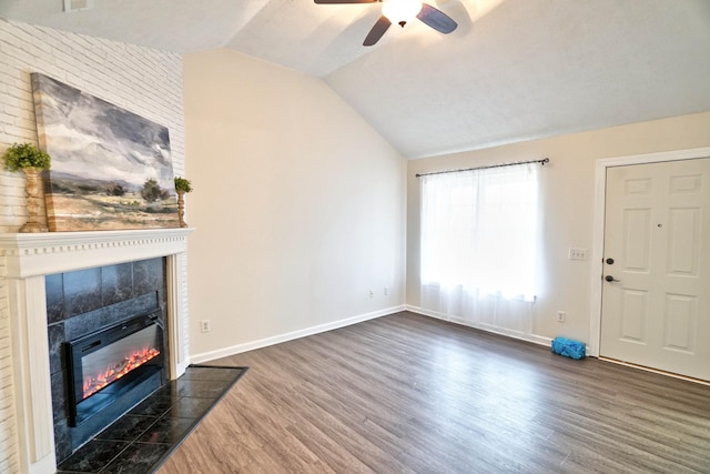 living room with a tile fireplace, dark wood-style floors, baseboards, ceiling fan, and vaulted ceiling