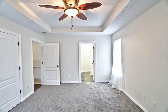 unfurnished bedroom with connected bathroom, baseboards, a raised ceiling, and carpet