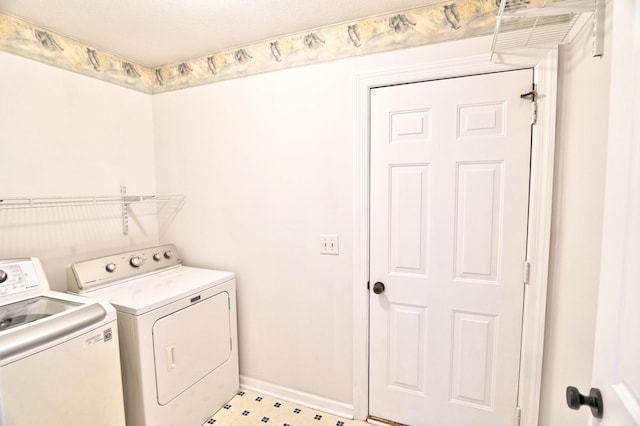 laundry area featuring washer and clothes dryer, laundry area, light floors, and baseboards