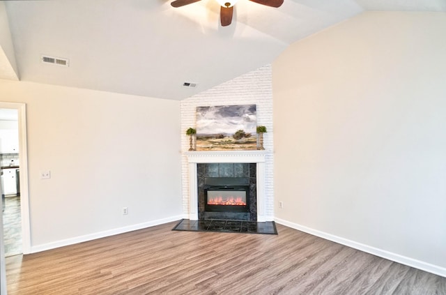 unfurnished living room featuring visible vents, wood finished floors, a fireplace, ceiling fan, and vaulted ceiling