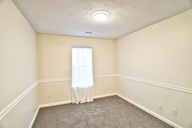 unfurnished room with visible vents, baseboards, a textured ceiling, and dark carpet