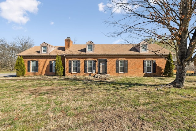 cape cod house with brick siding, a chimney, and a front lawn