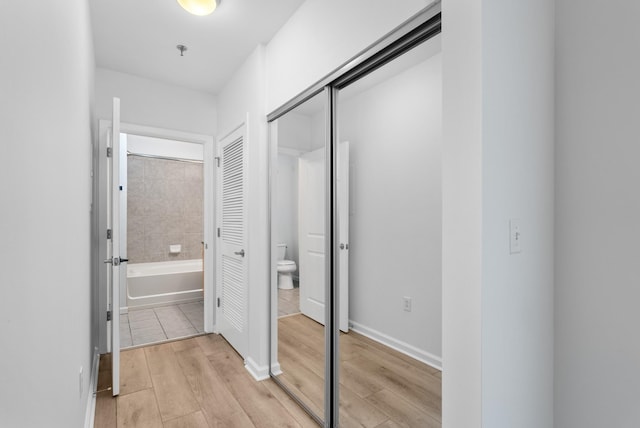 hallway featuring light wood-style flooring and baseboards