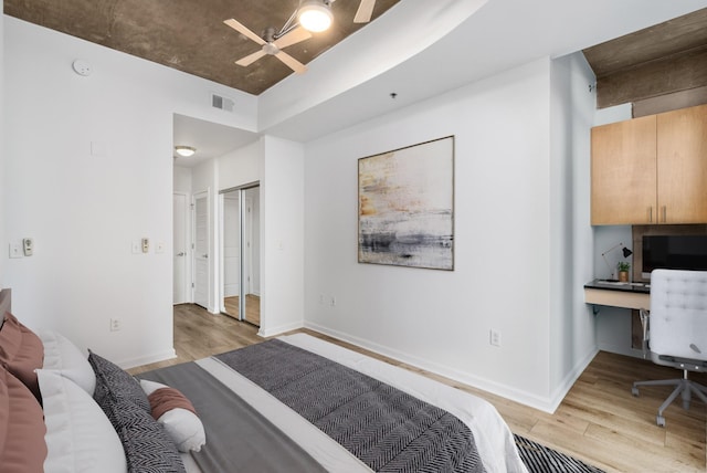 bedroom with baseboards, visible vents, light wood finished floors, and built in desk