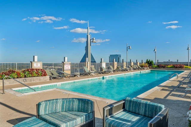 community pool with a patio area, outdoor lounge area, and fence