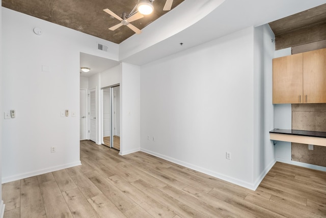 interior space with light wood-type flooring, baseboards, visible vents, and a ceiling fan