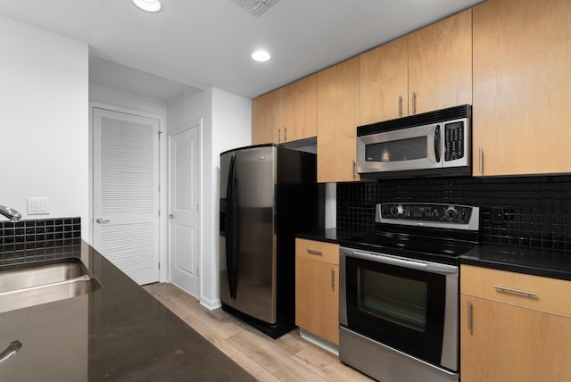 kitchen with dark countertops, backsplash, stainless steel appliances, and a sink