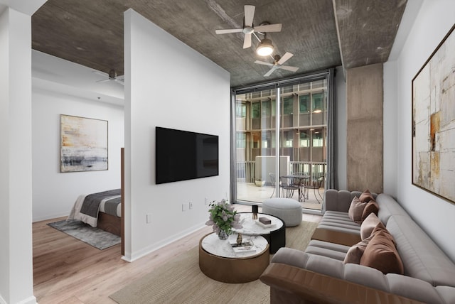 living room with light wood finished floors, baseboards, ceiling fan, and expansive windows