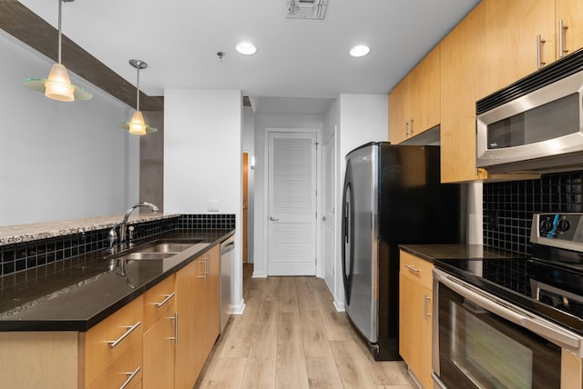 kitchen featuring backsplash, recessed lighting, light wood-style floors, stainless steel appliances, and a sink