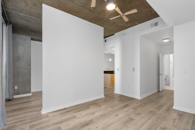 empty room with visible vents, a ceiling fan, light wood-type flooring, and baseboards