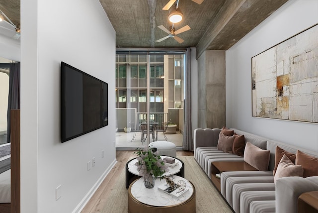 living area featuring a ceiling fan, floor to ceiling windows, wood finished floors, and baseboards