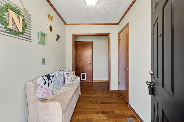 hallway featuring visible vents, baseboards, dark wood-style flooring, a textured ceiling, and crown molding