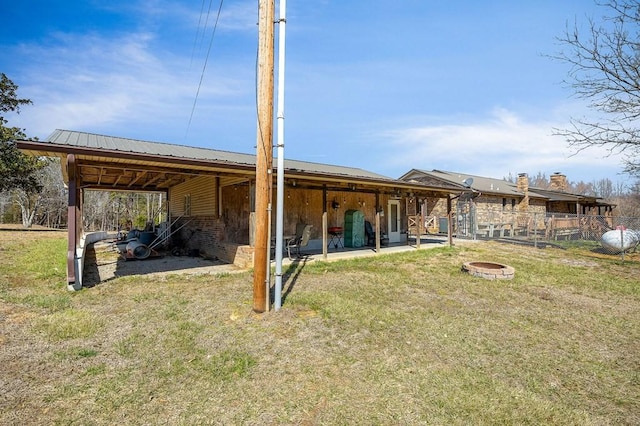 back of house featuring an outdoor fire pit and metal roof