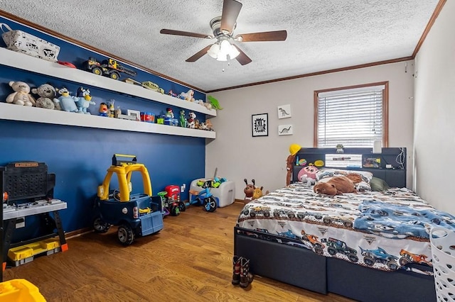 bedroom with ceiling fan, a textured ceiling, wood finished floors, and ornamental molding