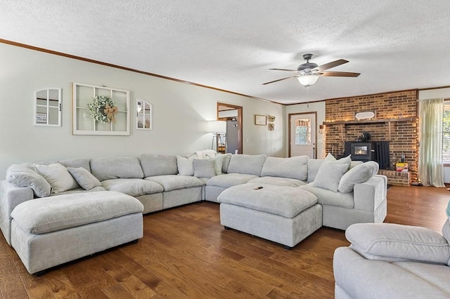 living room featuring a textured ceiling, a wood stove, and dark wood-style flooring