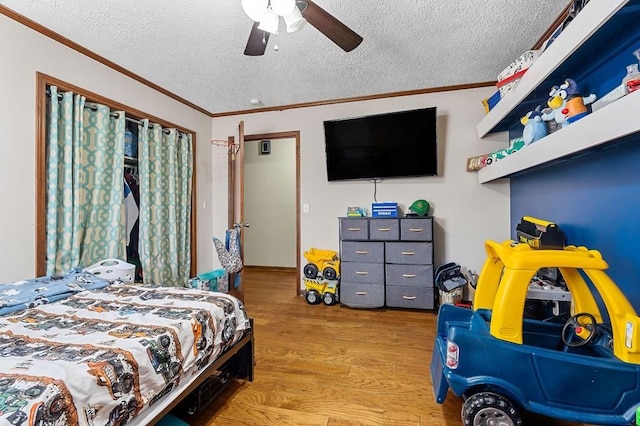 bedroom featuring ornamental molding, a textured ceiling, a ceiling fan, and wood finished floors