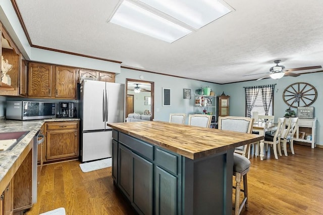 kitchen featuring appliances with stainless steel finishes, a breakfast bar, wood counters, and wood finished floors