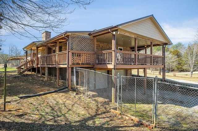 view of side of property with fence, a wooden deck, a chimney, an attached garage, and a gate