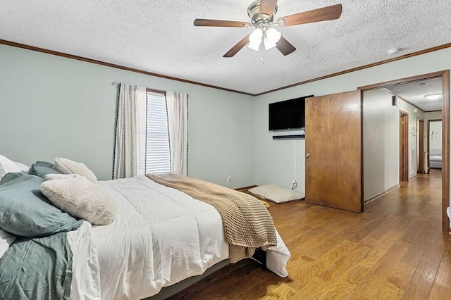 bedroom with ceiling fan, crown molding, wood finished floors, and a textured ceiling